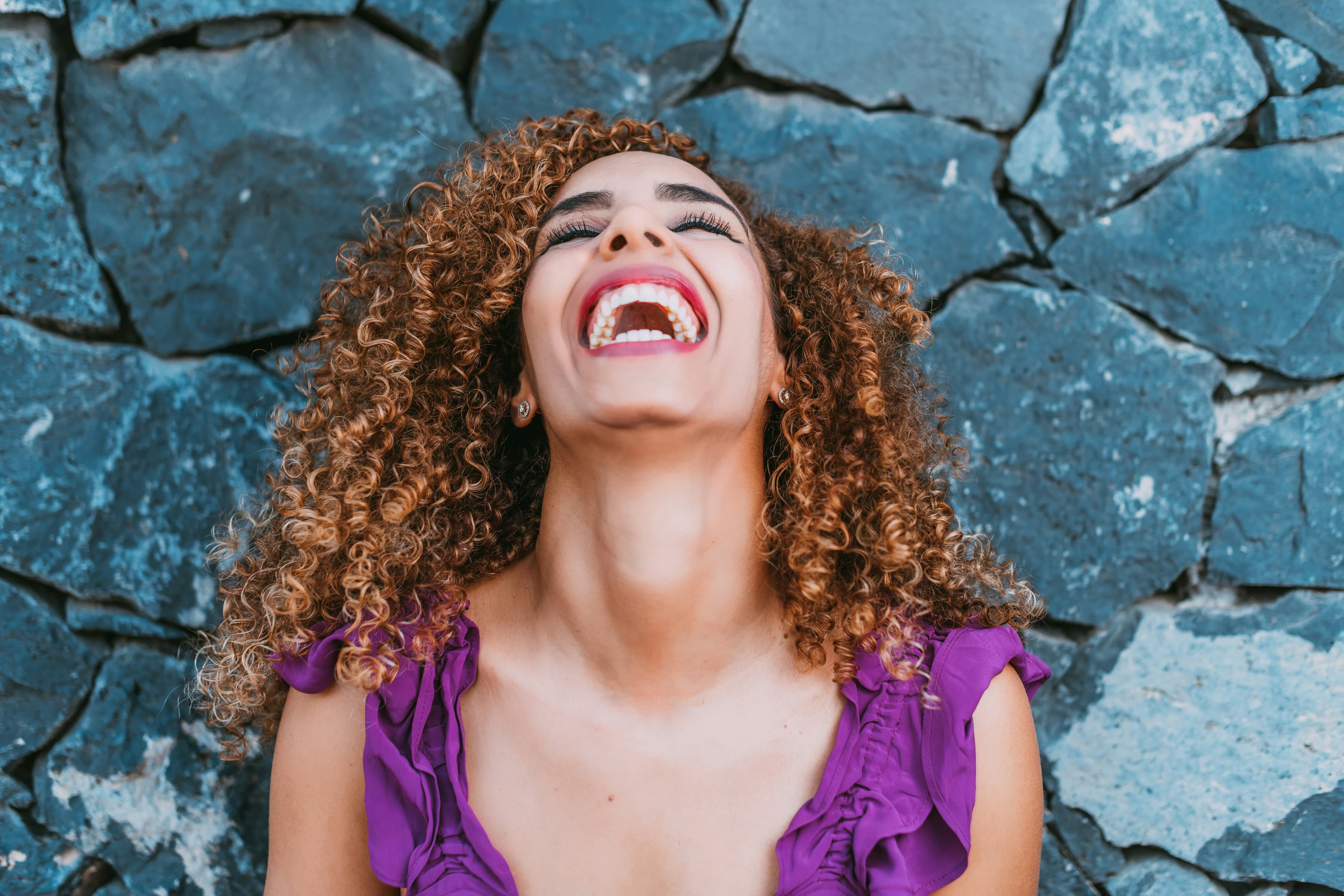 a woman with curly hair laughing and looking up
